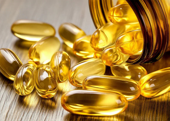 Golden omega-3 fish oil softgel capsules spilling from amber bottle on wood surface