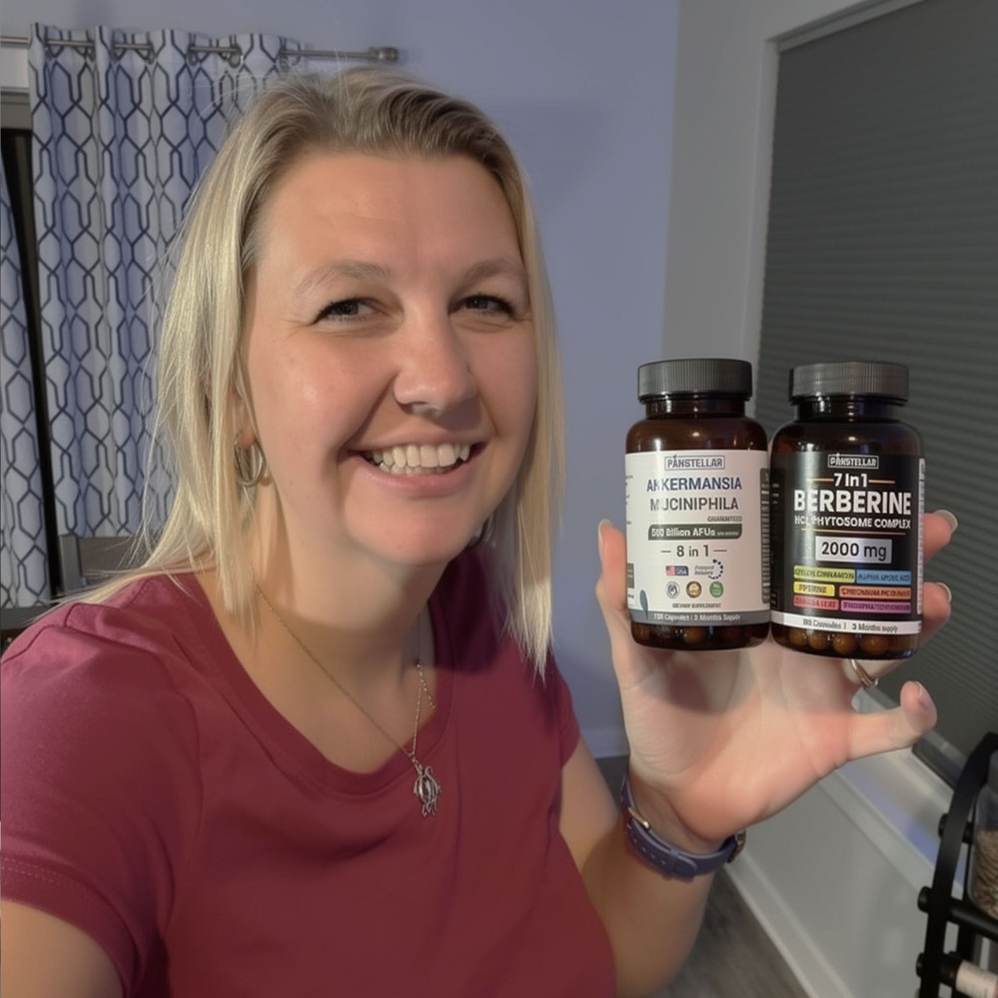 Smiling woman indoors holding Akkermansia muciniphila and Berberine supplement bottles.